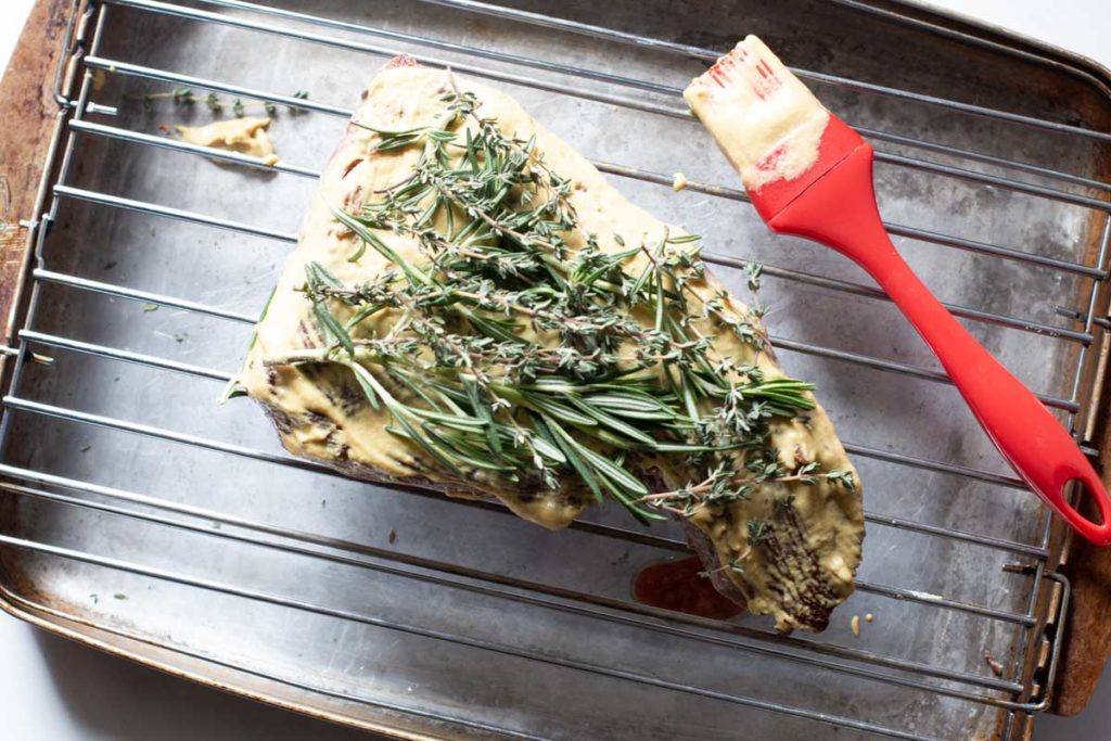 Beef tri tip recipe topped with Dijon mustard and fresh rosemary and thyme