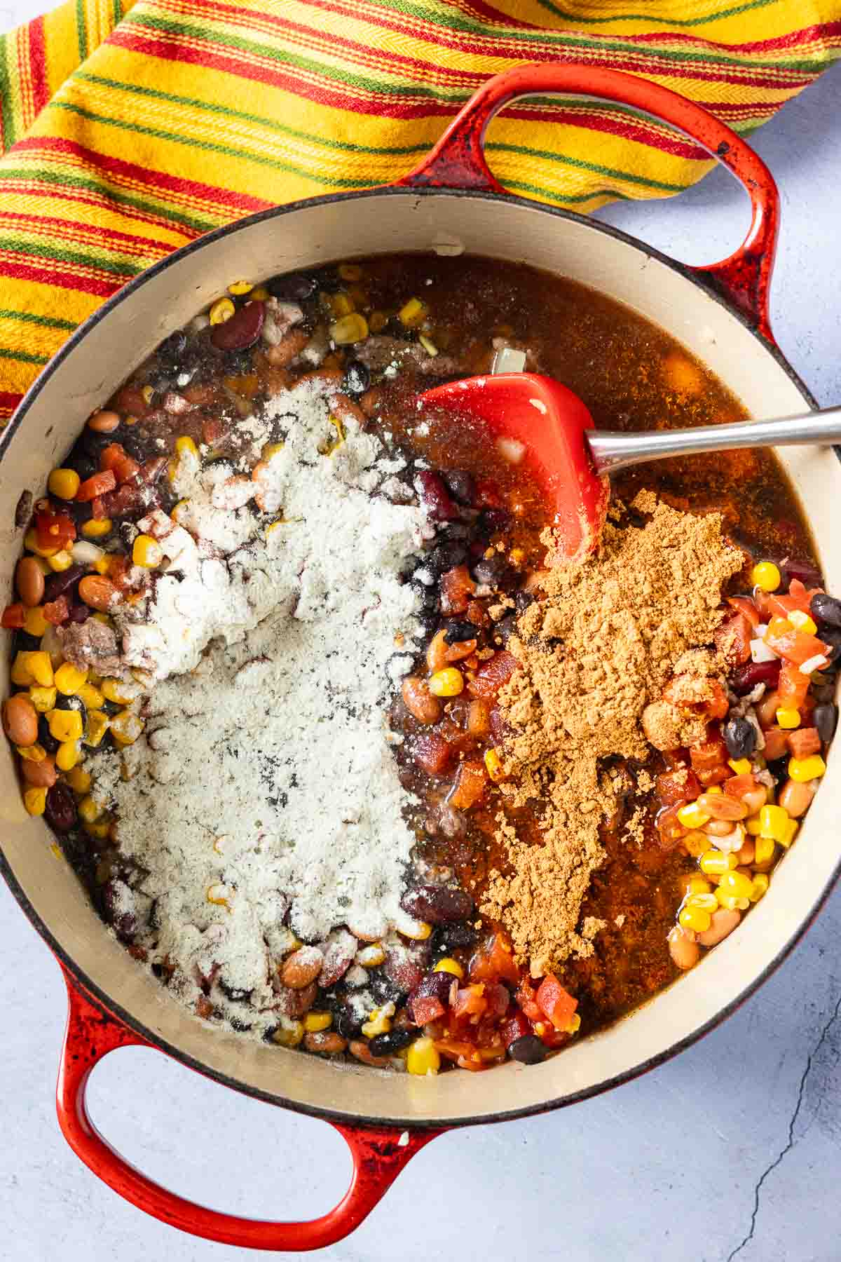 Adding ranch dressing and taco seasoning to taco soup with ranch dressing.