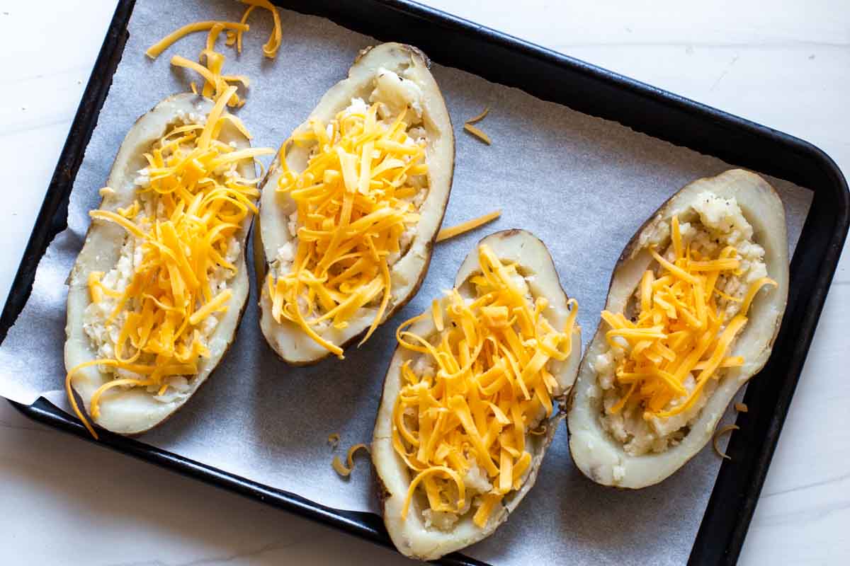 Adding cheese to twice baked breakfast potatoes.