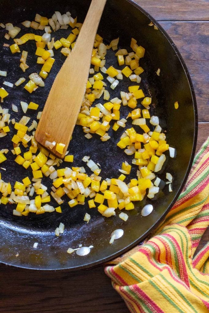 cooking chopped yellow bell peppers and onions