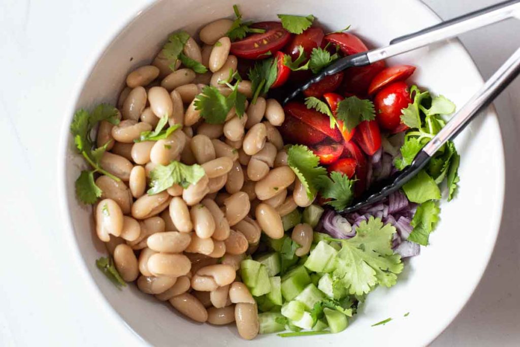 Mixing beans and chopped vegetables for shrimp and avocado salad
