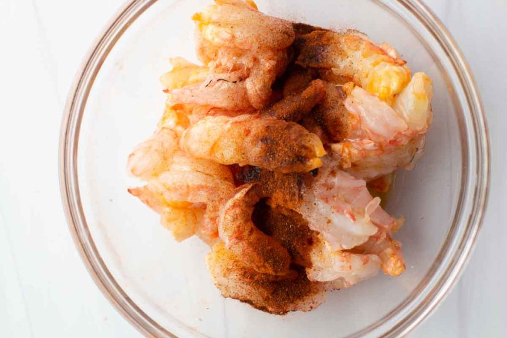 Shrimp in a bowl tossed with olive oil and chipotle chile powder