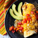 Green chile smothered brurrito topped with melted cheese and green chile and diced red and yellow tomatoes