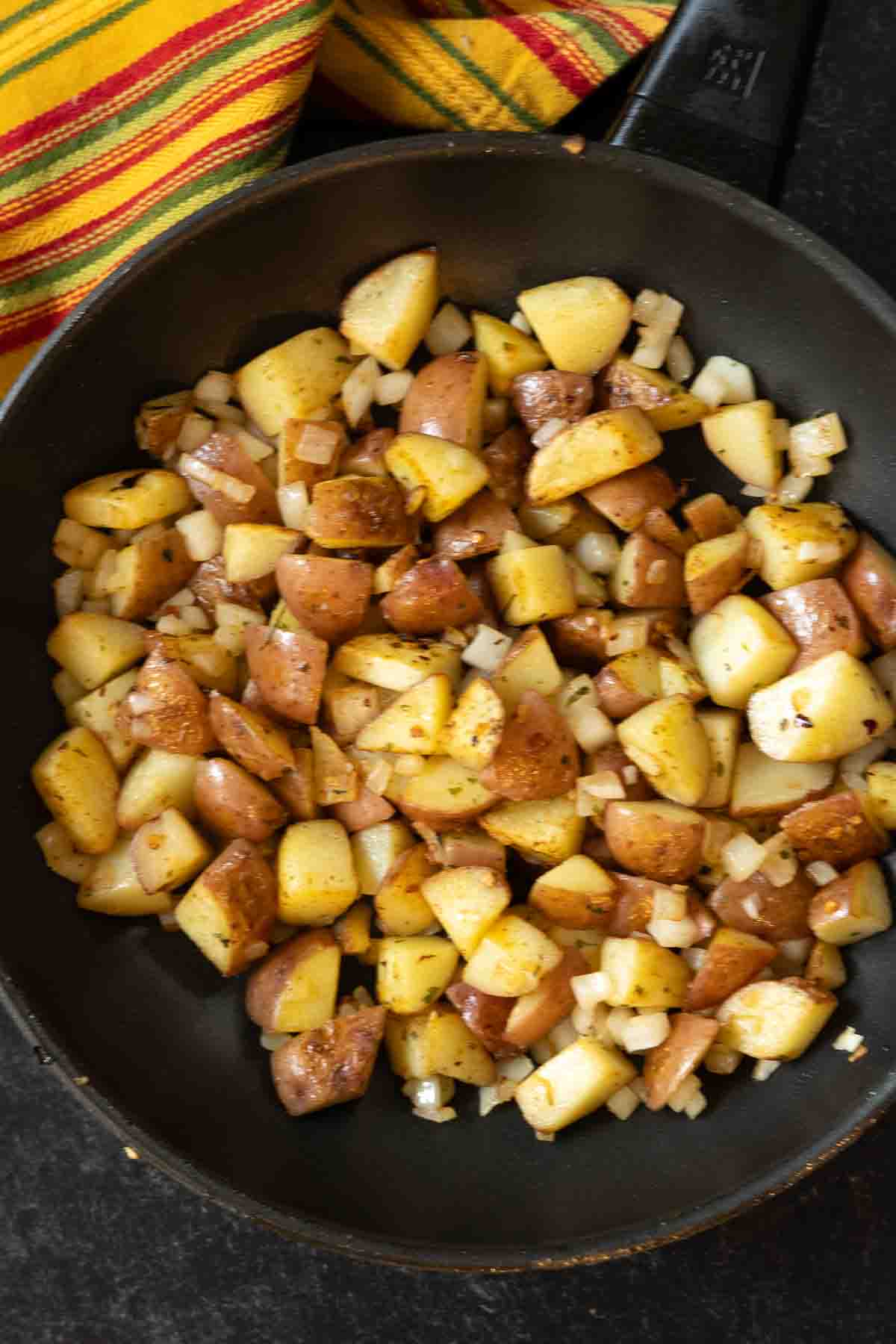 Frying potatoes to make smothered breakfast burritos with potatoes.