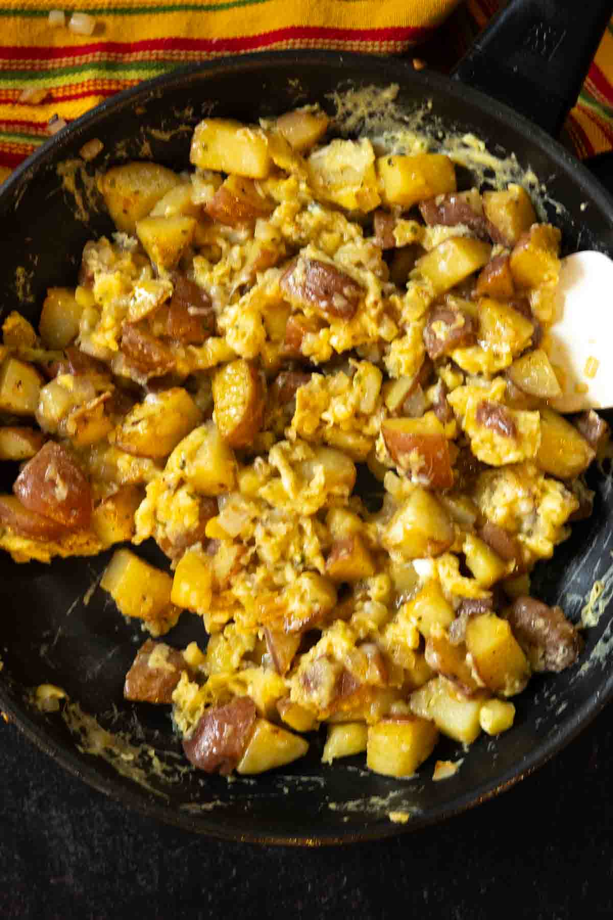 Mixing eggs with potatoes to make breakfast burritos with potatoes.