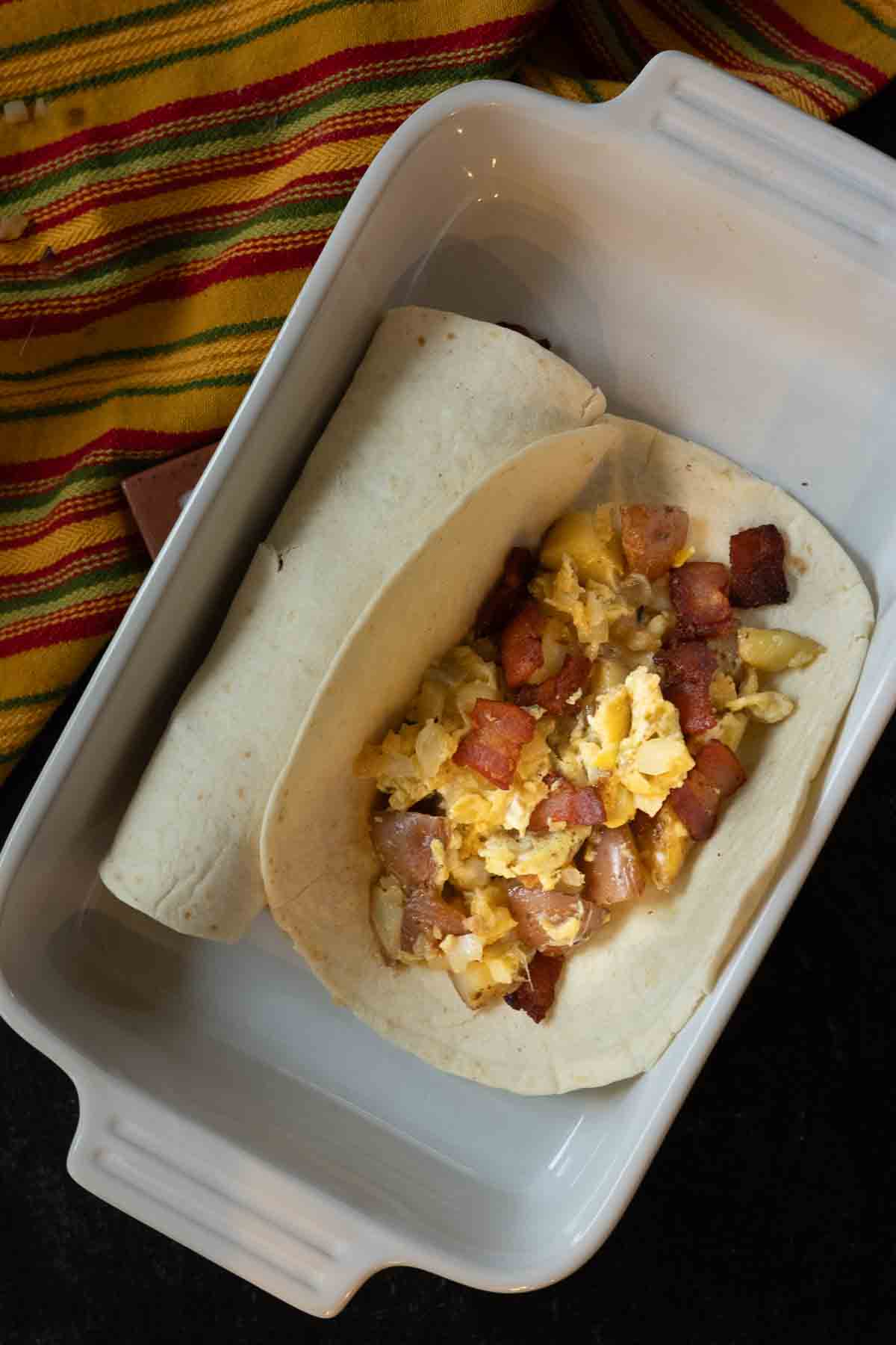 Filling flour tortillas with eggs, potatoes and bacon.