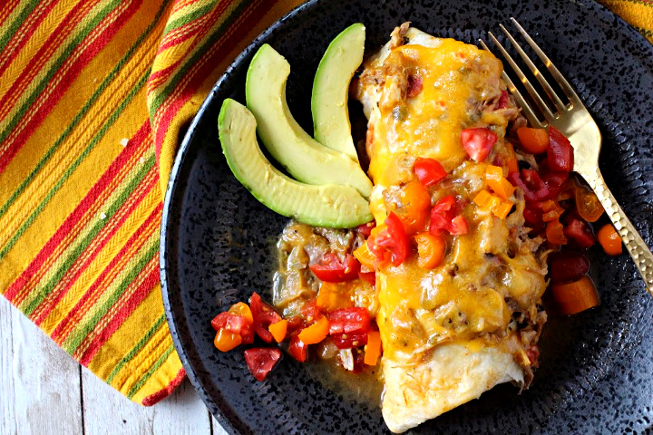 Green chile smothered brurrito topped with melted cheese and green chile and diced red and yellow tomatoes