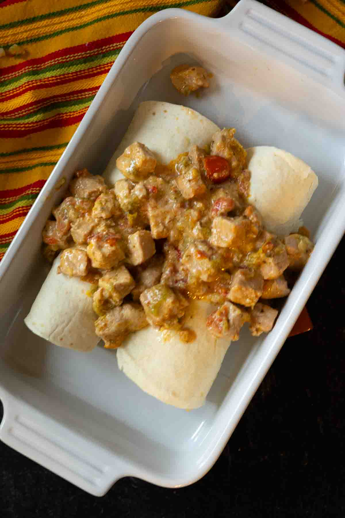 Topping breakfast burritos with potatoes with green chili.