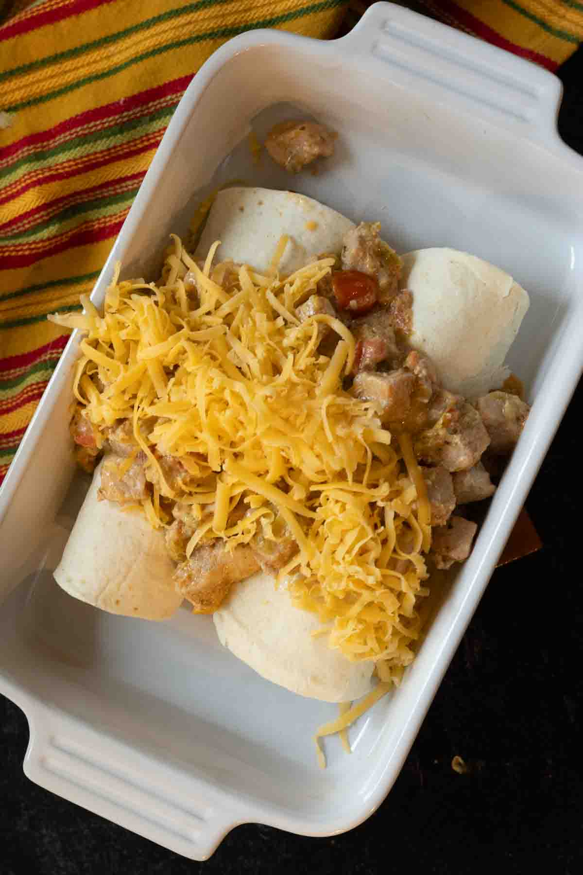 Topping breakfast burritos with potatoes with grated cheese.