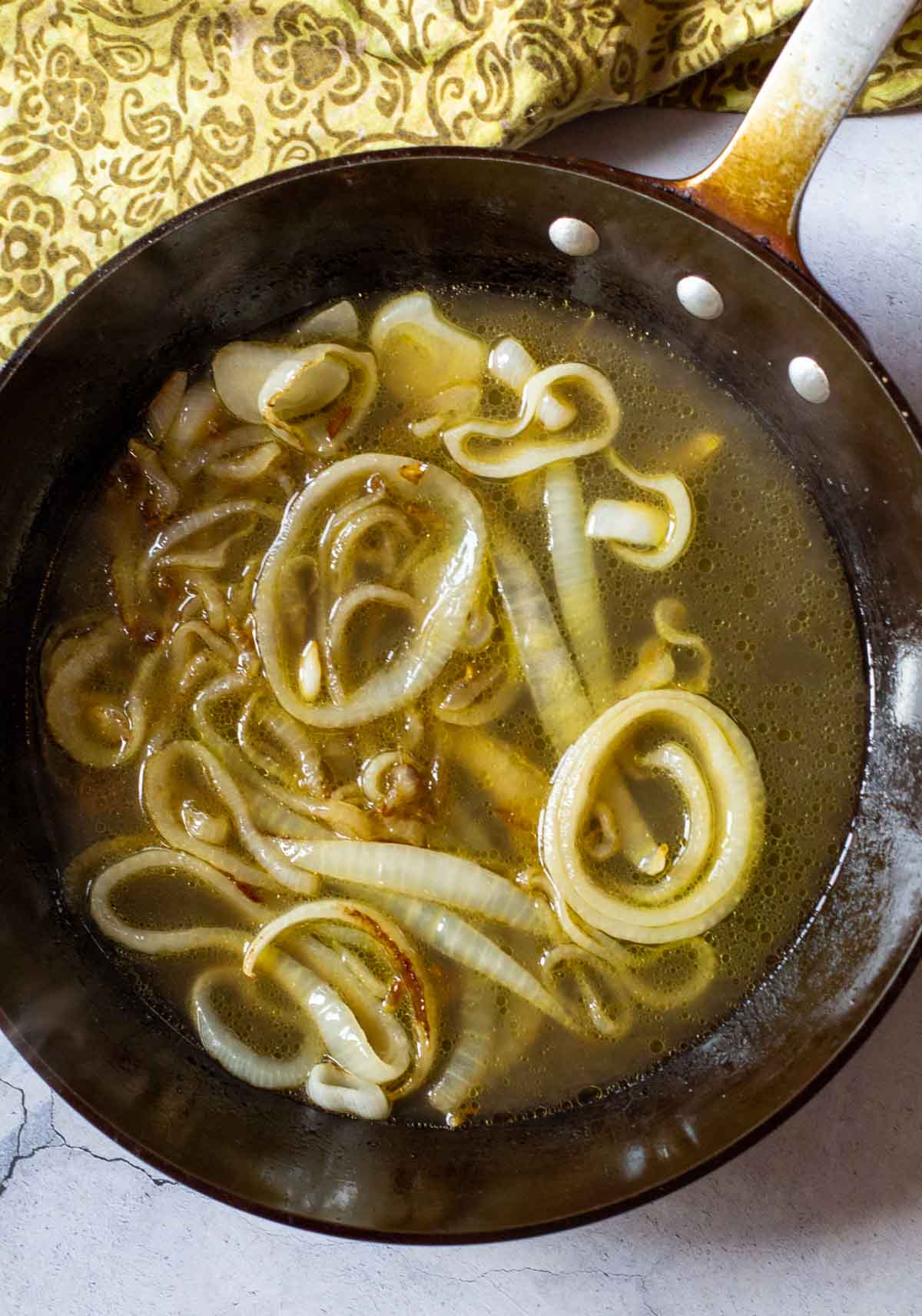 Adding beer to onions to make brats and kraut.