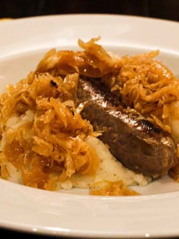 Mashed potatoes topped with bratwurst and sauerkraut.
