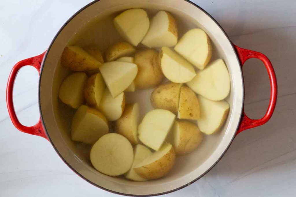 potatoes cut in cubes in a le creuset dutch oven covered with water