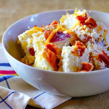 Loaded baked potato salad in a white serving bowl.