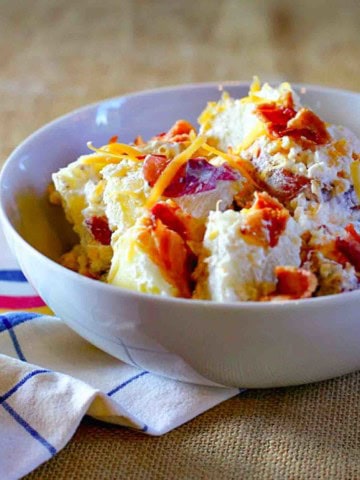 Loaded baked potato salad in a white serving bowl.