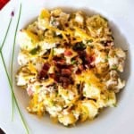 Potato salad with bacon served in a white bowl.