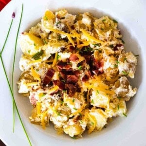 Potato salad with bacon served in a white bowl.