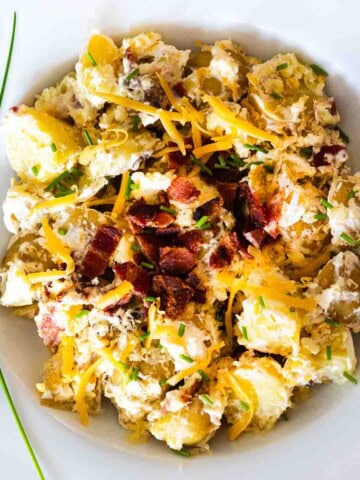 Potato salad with bacon served in a white bowl.