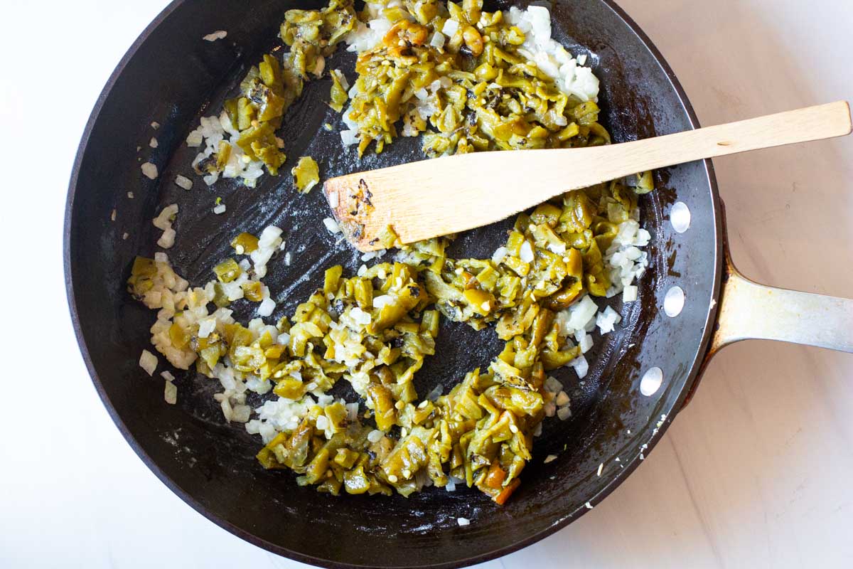 Adding hatch green chile peppers to fry pan to make sauce