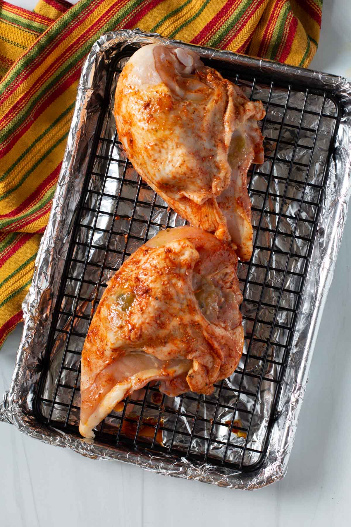 Roasting achiote chicken on a sheet pan with a wire rack.