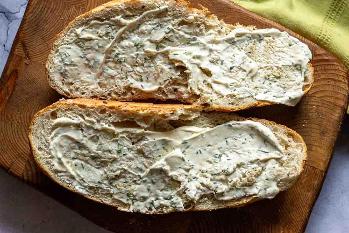 A loaf of French bread split horizontally and spread with lemony mayonnaise.