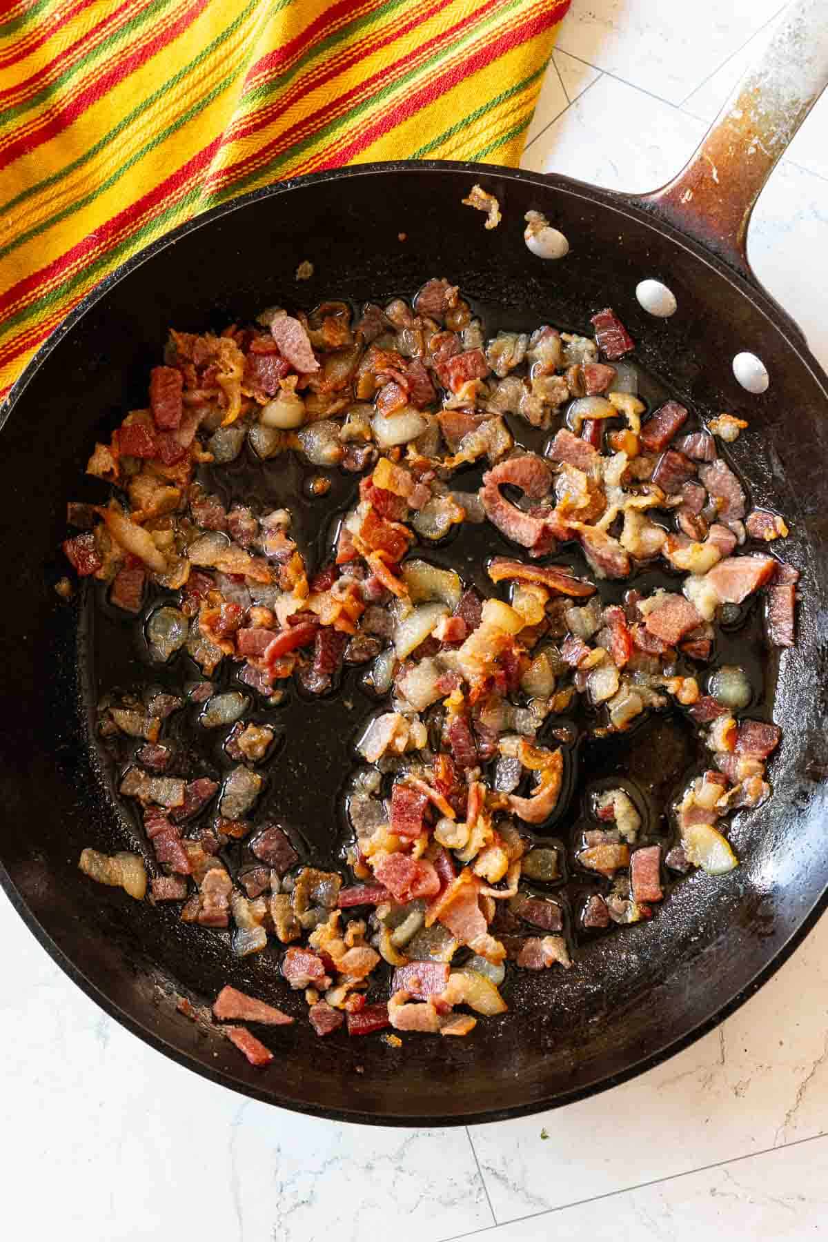 Frying chopped bacon to make calico beans.
