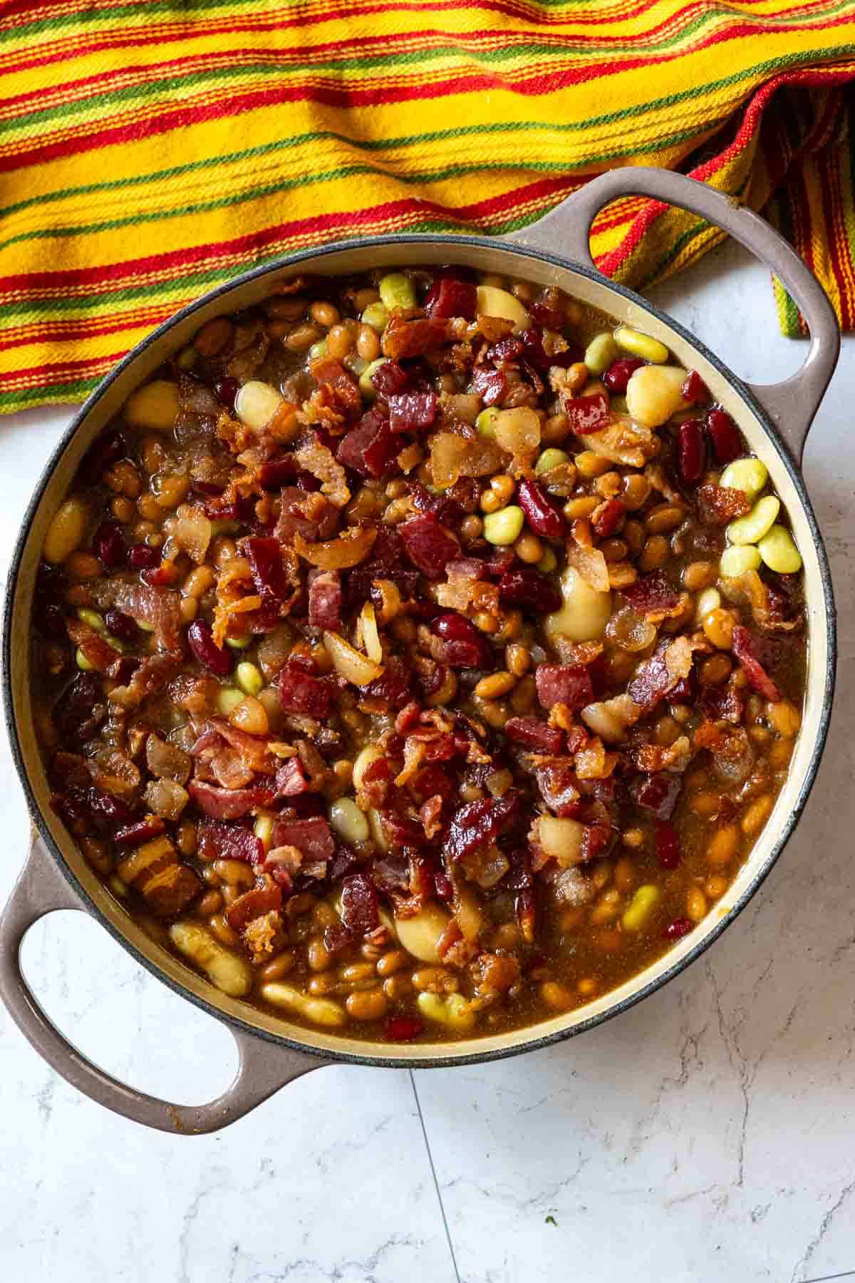 Adding calico beans to a dutch oven to be baked.