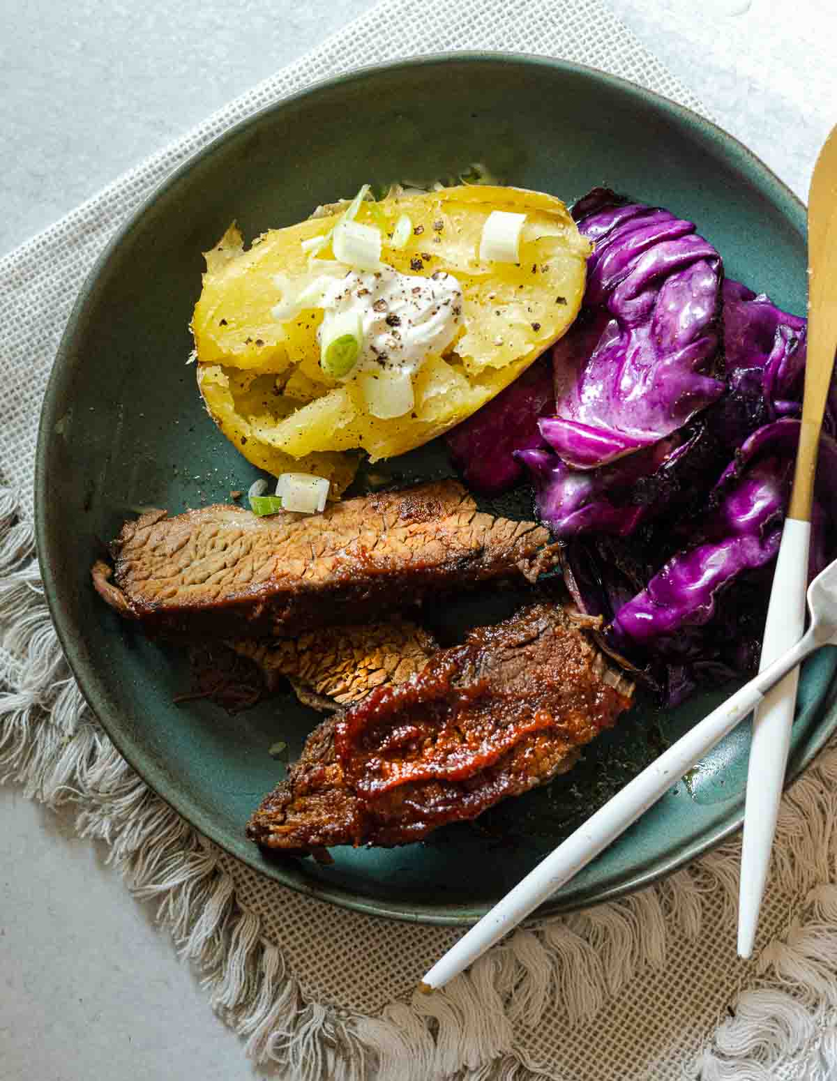 sliced Oven brisket served with baked potato and fried cabbage.