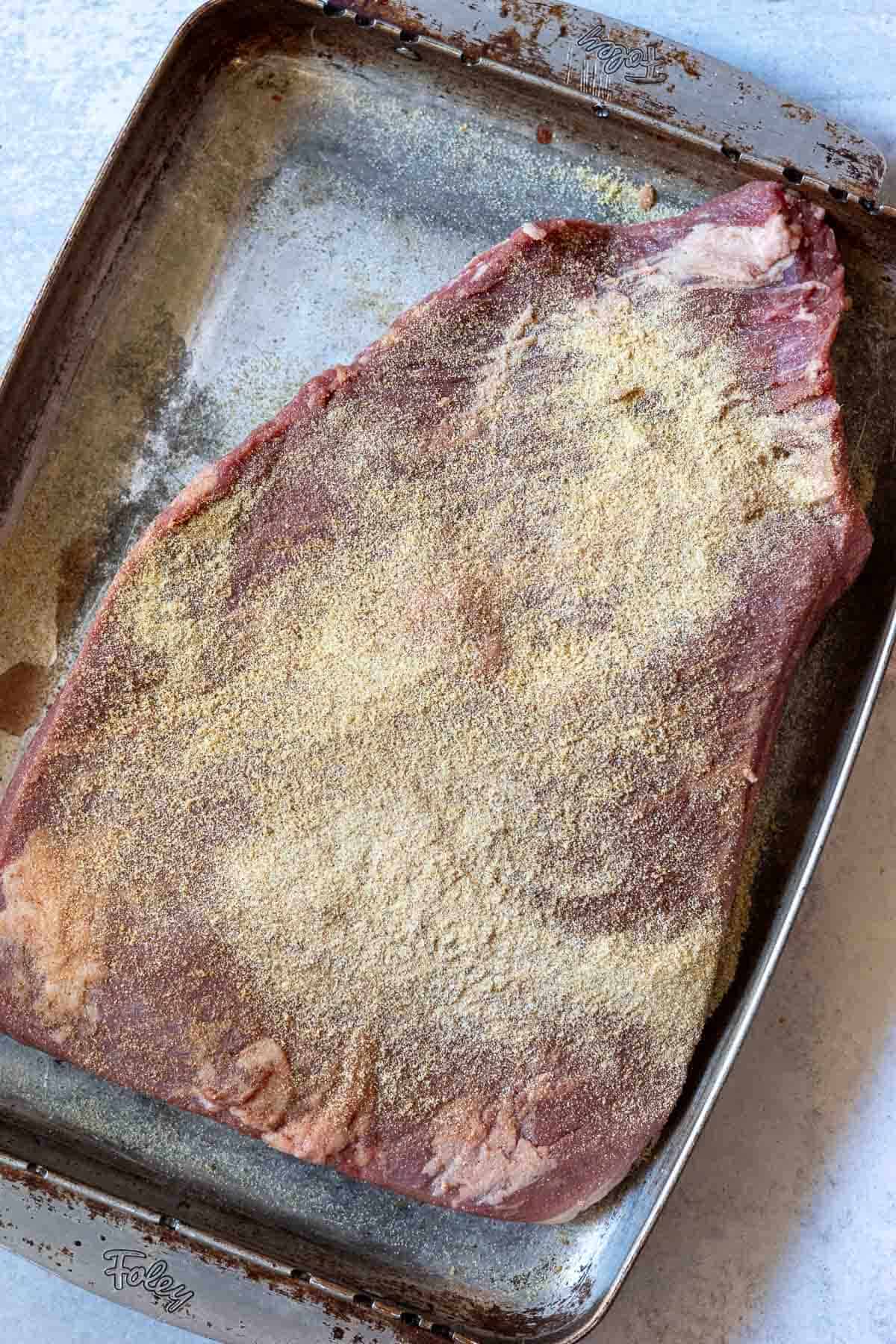 Seasoning a brisket to bake in the oven.