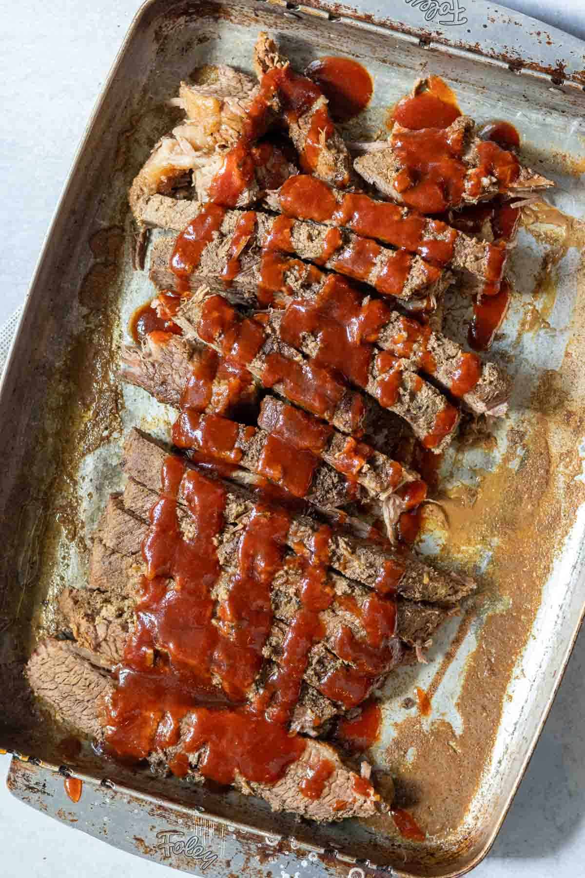 Drizzling bbq sauce on top of oven brisket.