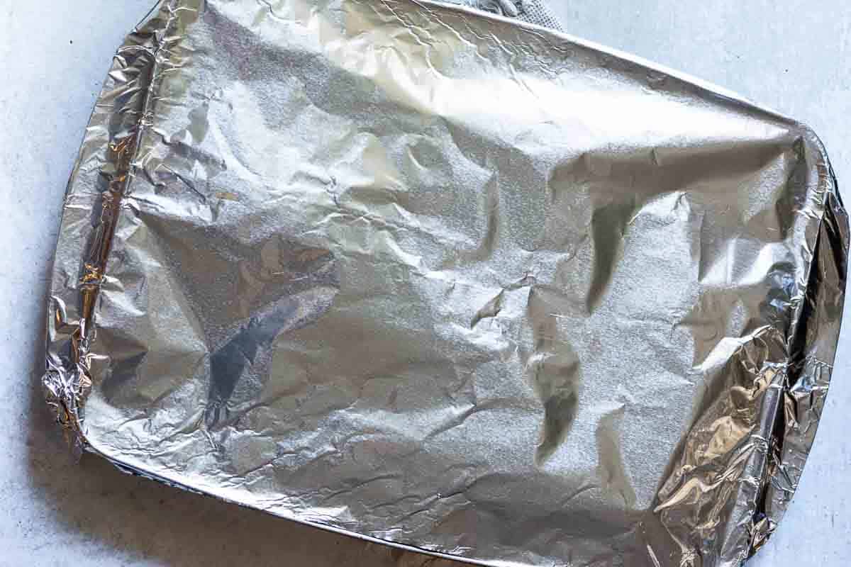 Oven brisket in a roasting pan covered with aluminum foil.