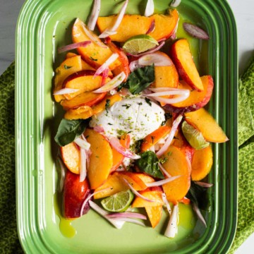 Salad with Peaches and Burrata on a green platter.