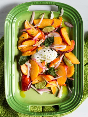 Salad with Peaches and Burrata on a green platter.