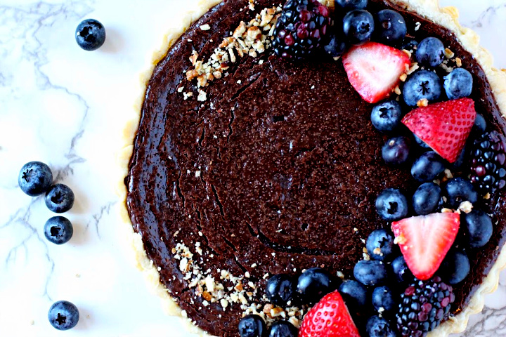 Creamy chocolate tart recipe topped with chopped nuts and barries