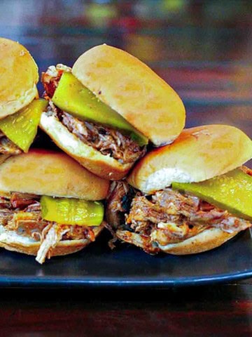 Dr. Pepper pulled pork sliders on a black platter.