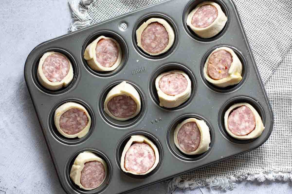 Sliced sausage in.a blanket in a mini-muffin pan.