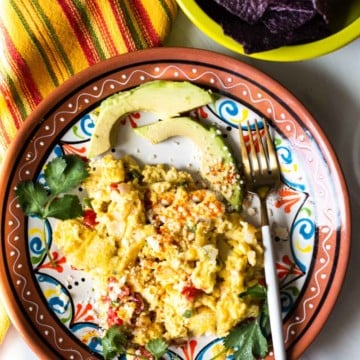 Mexican scrambled eggs with sliced avocado.