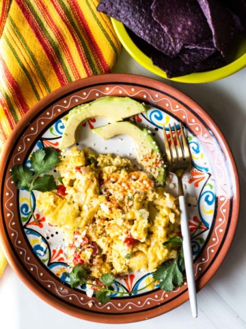 Mexican scrambled eggs with sliced avocado.