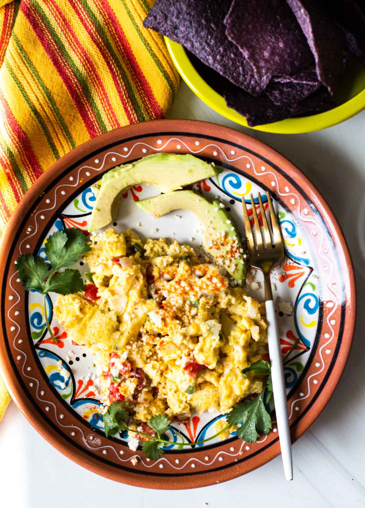 Mexican scrambled eggs with sliced avocado.