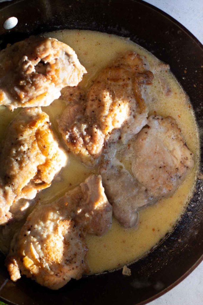 Adding fried boneless skinless chicken thighs to lemon cream sauce.