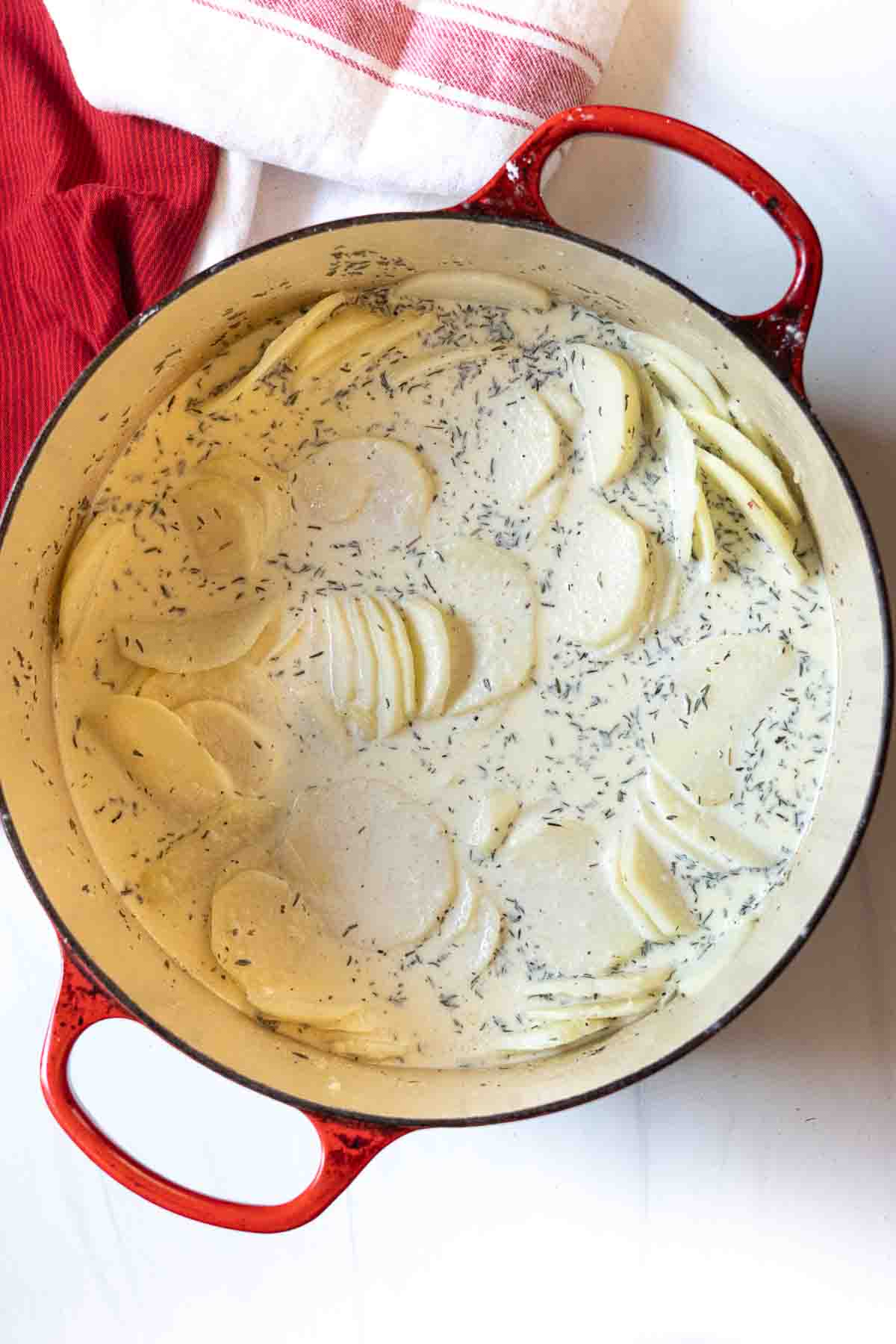 Cooking potatoes in cream to make scalloped potatoes.