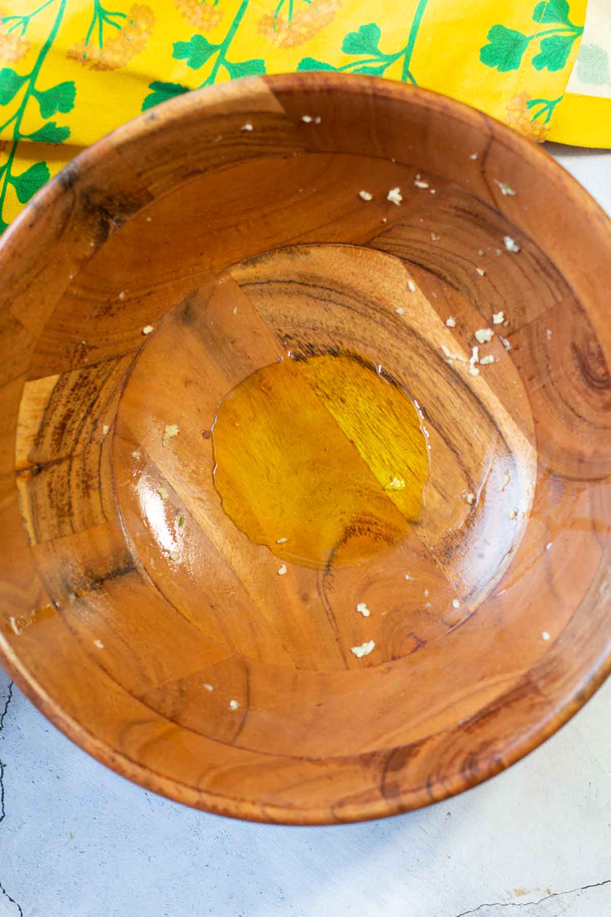 Spreading garlic on the sides of a wooden salad bowl.