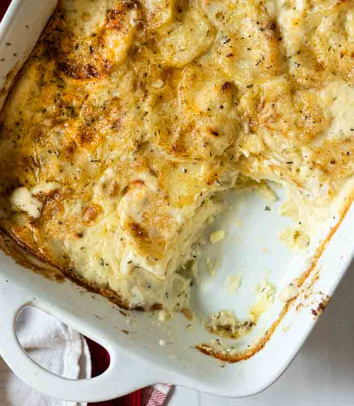 Baked gluten free scalloped potatoes in a white casserole dish.