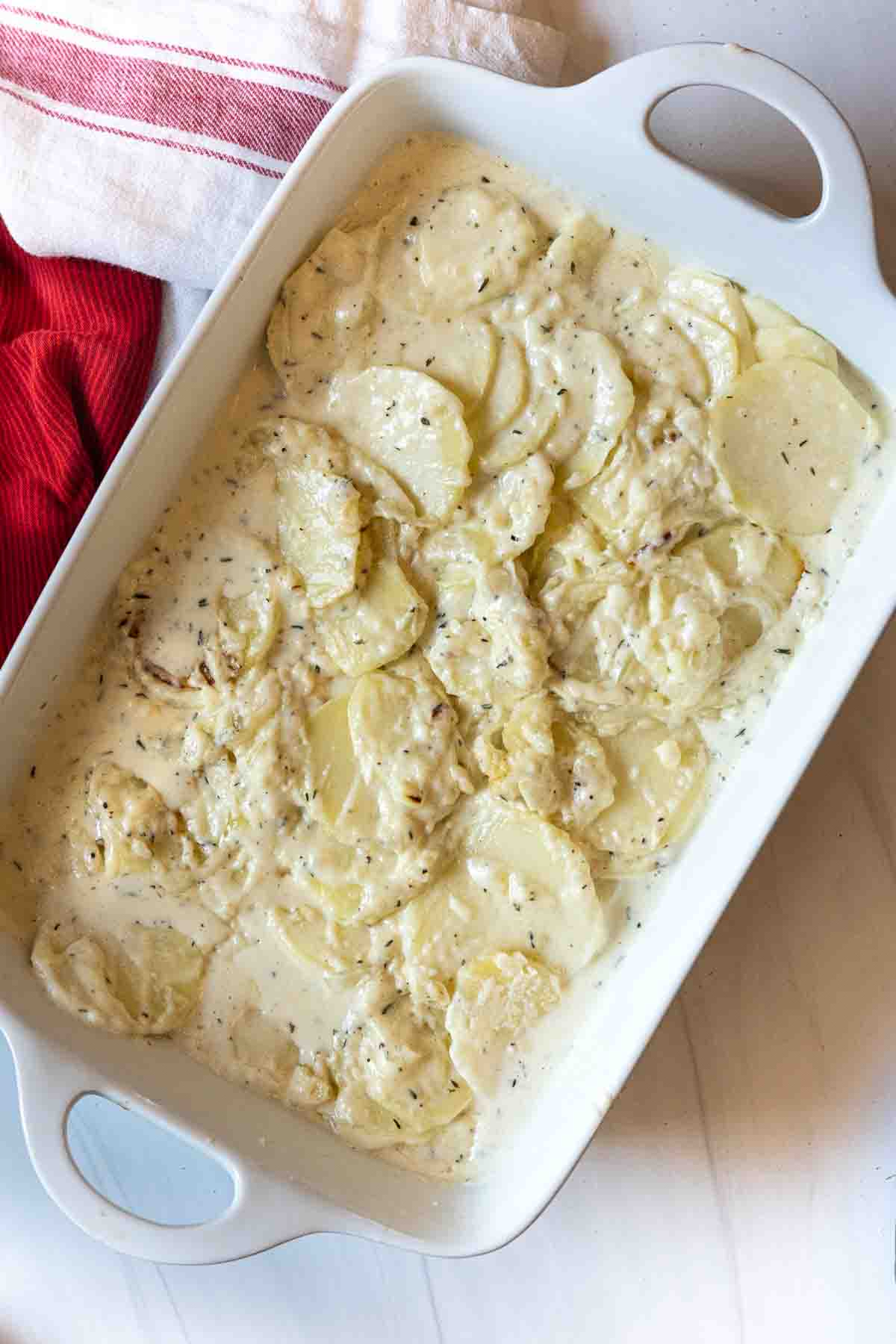 Scalloped potatoes in a casserole dish ready to be baked.