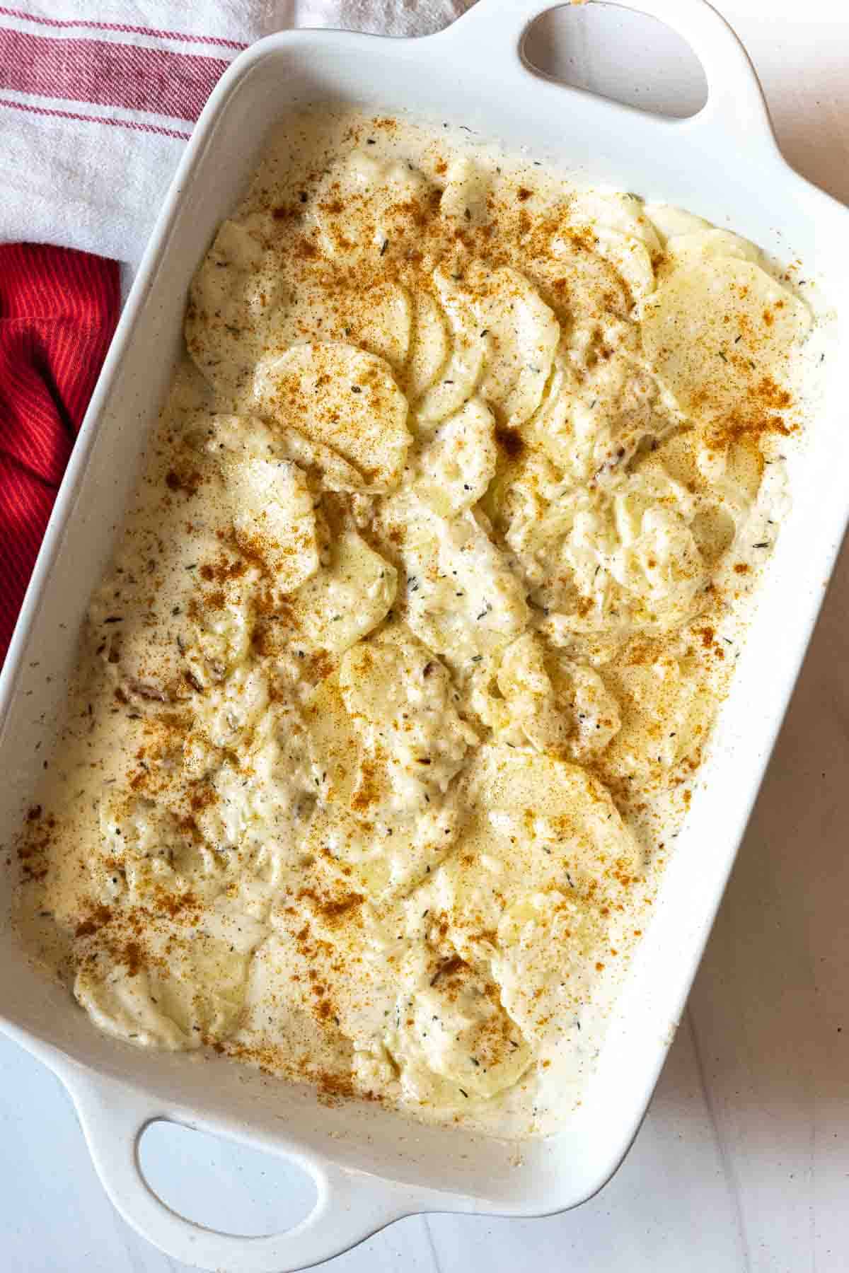 Sprinkling scalloped potatoes with paprika before baking.
