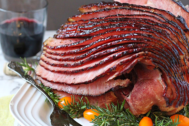 A spiral cut ham with honey thyme glaze and a glass of red wine.