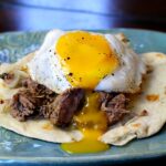 Beef Machaca Huevos. Mexican shredded beef is served on a flour tortilla and topped with an egg.