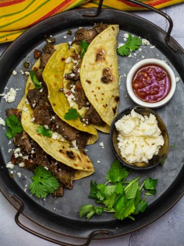 Beef machaca tacos served with cotija cheese and salsa.