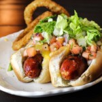 Two taco hot dogs on a white plate.