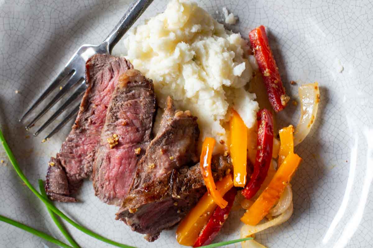 Pan fried buffalo steak with bell peppers and mashed potatoes.