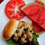 Southwest ground chicken burgers with a slice of tomato and watermelon for a side.